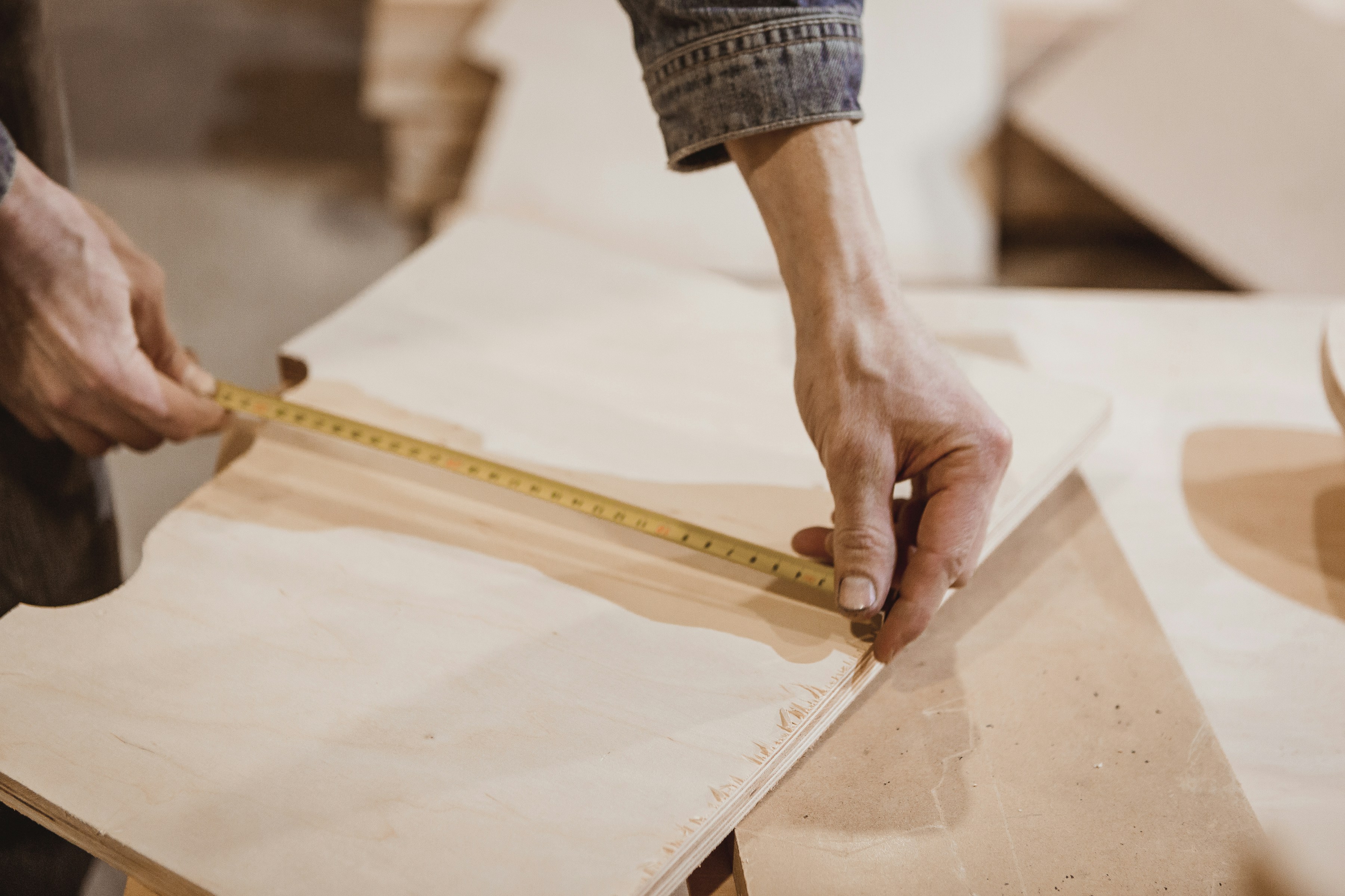 Craftsman measuring plywood before cutting